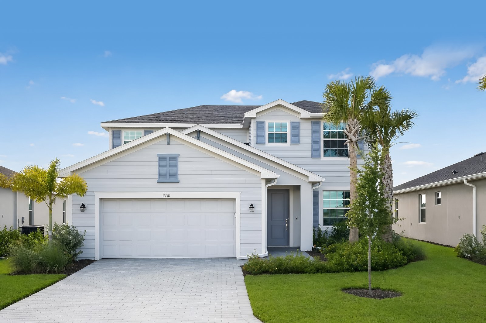 Photograph of a completed two-storey Amalfi home at Turnleaf in Punta Gorda, seen from the street with a paver driveway and young palms in the front garden.