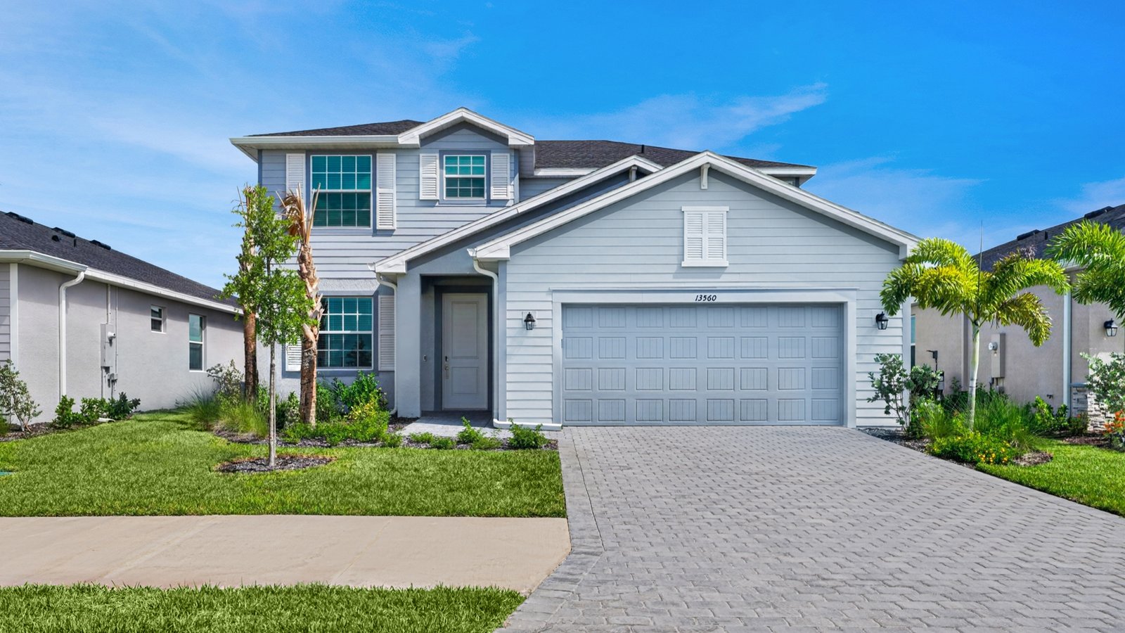 Photograph of a completed two-storey Lennar home on Turnleaf Boulevard in Punta Gorda, with a paver driveway, two-car garage and young palms in the front garden.