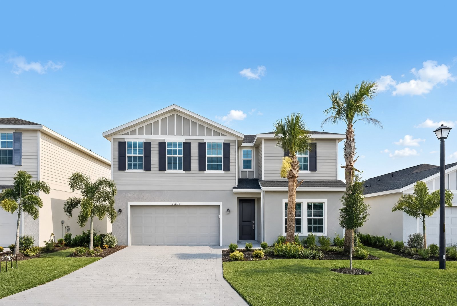 Photograph of a completed two-storey Segan home at Turnleaf in Punta Gorda, seen from the street with palms in the front garden and neighbouring houses either side.
